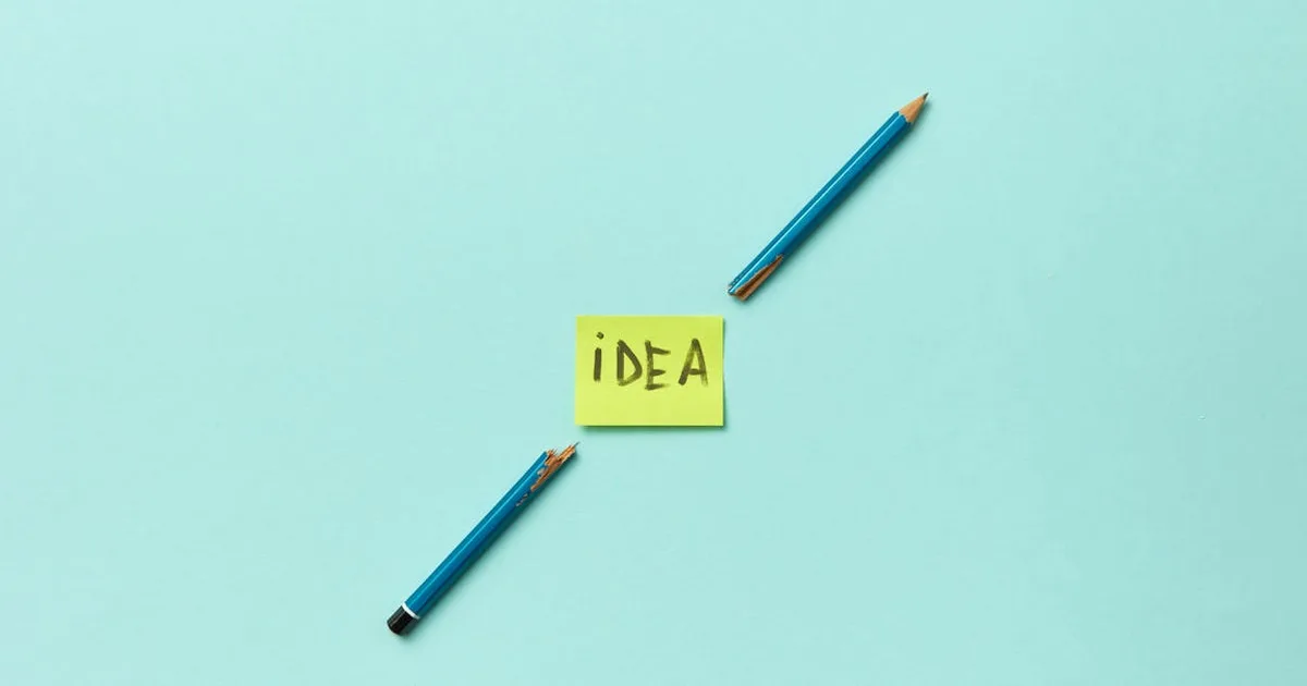 Conceptual photo of a broken pencil with a sticky note labeled 'idea' on a blue background.