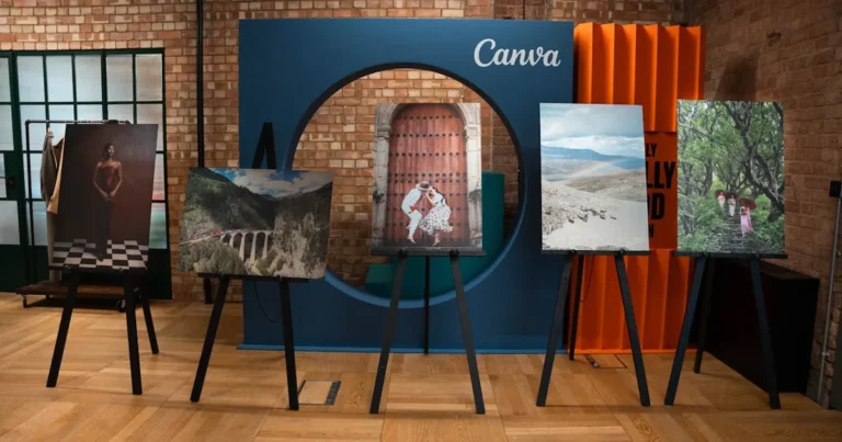 A modern indoor art exhibition showcasing diverse photography on easels against a brick wall.