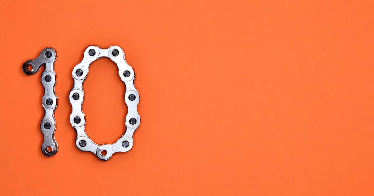 Bicycle chain arranged to form the number ten against a bright orange background.