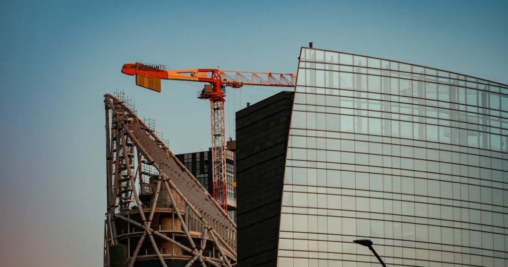 A towering crane at a construction site next to a modern skyscraper, capturing urban development.