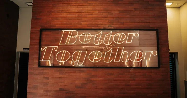 Neon 'Better Together' sign on brick wall adds warmth to modern interior.