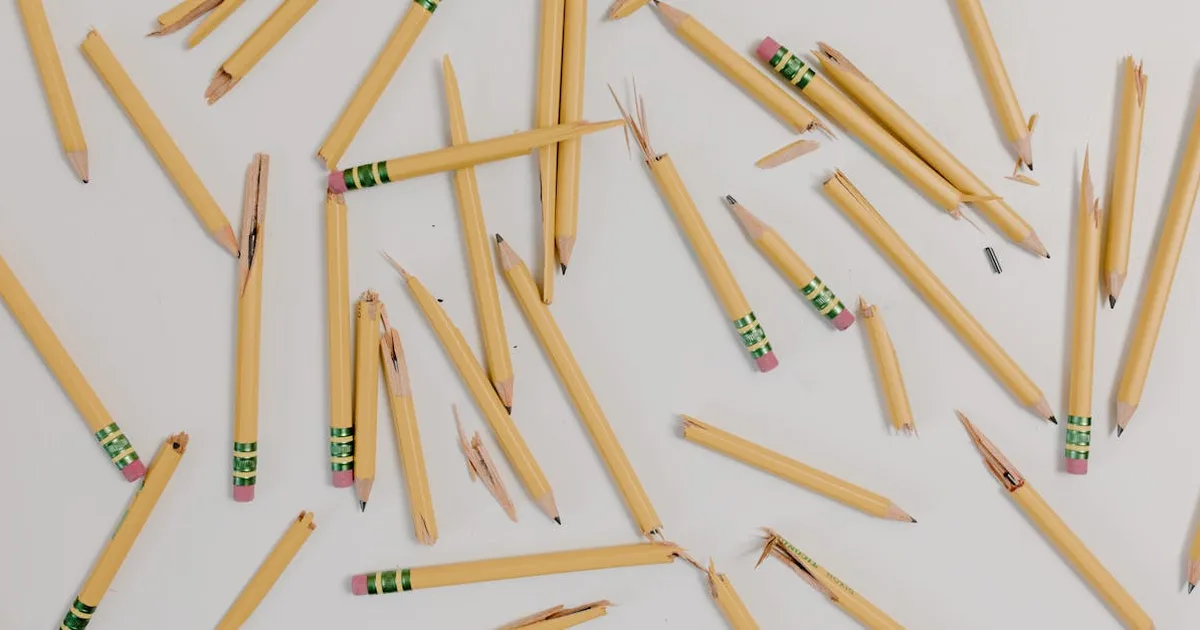 A flat lay of broken pencils scattered on a white background.