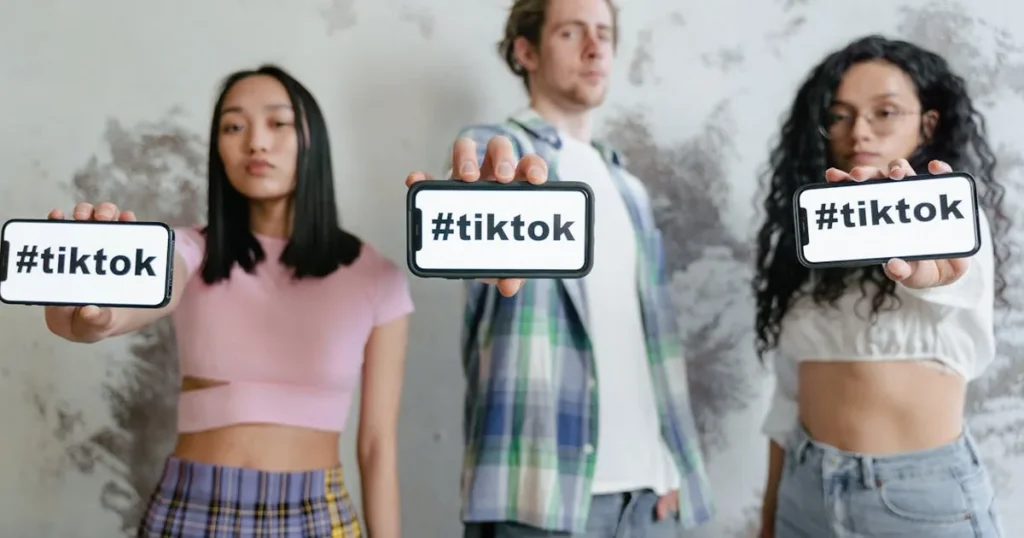 Group of young adults holding phones with #tiktok indoors, showcasing social media culture.
