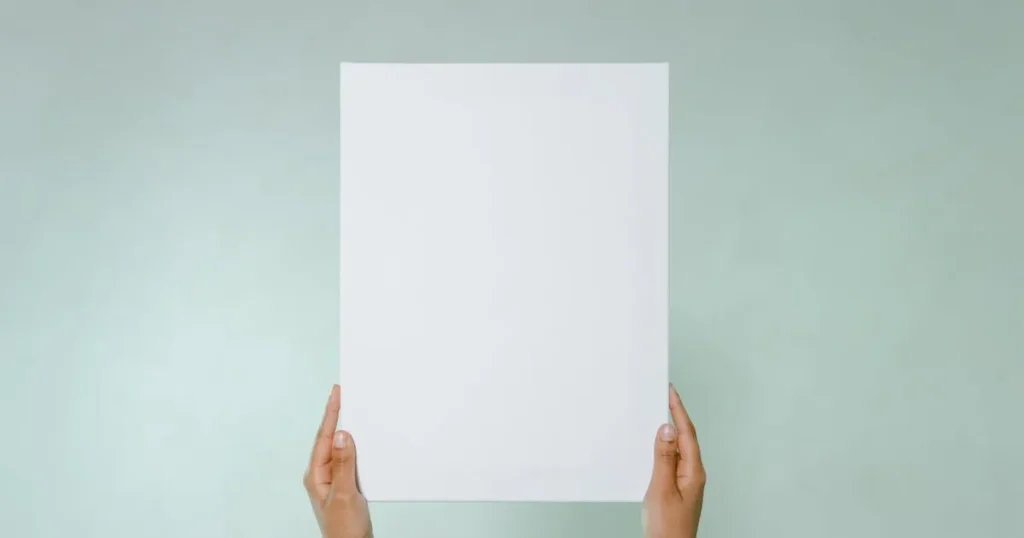 Simple blank canvas held hands on light green background with copy space.