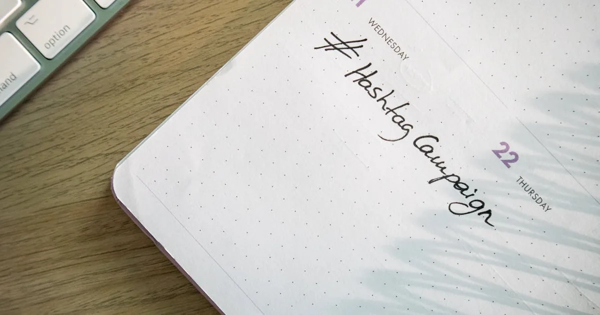 Open planner with 'Hashtag Campaign' handwritten next to keyboard. Ideal for social media and produc