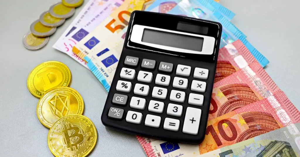Calculator with euro banknotes and cryptocurrency coins like Bitcoin on a table.